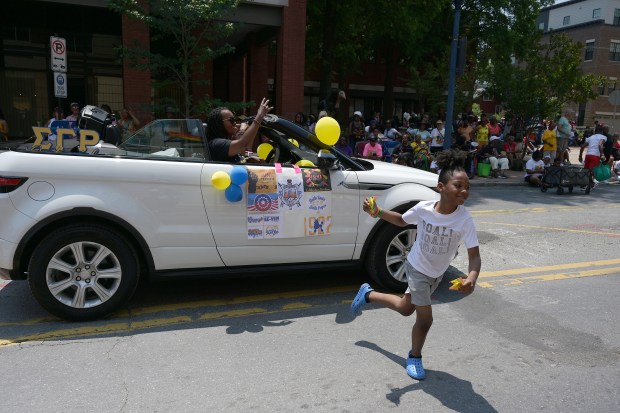 Zasere Wallace, 8, grabs some candy from a parade car passing by. The Annapolis Juneteenth Parade makes its way up West Street Saturday afternoon. (Paul W. Gillespie/Staff photo)