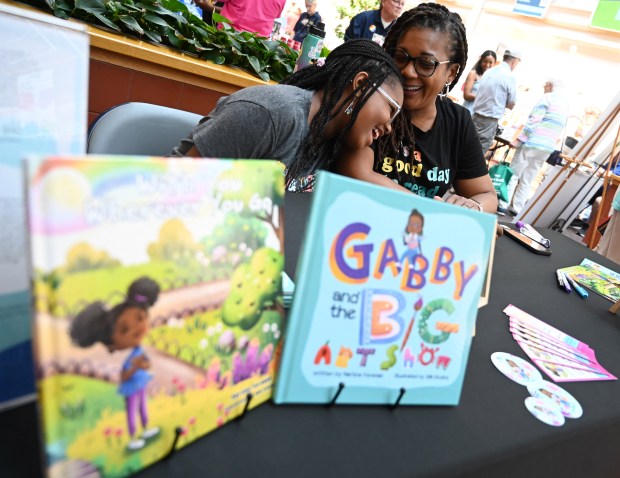 Eldersburg author Martine Foreman shares a moment with her 11-year-old daughter Jada, while promoting her picture books at her vendor table during the Juneteenth in Carroll celebration at Carroll Community College on Saturday. (Brian Krista/staff photo)