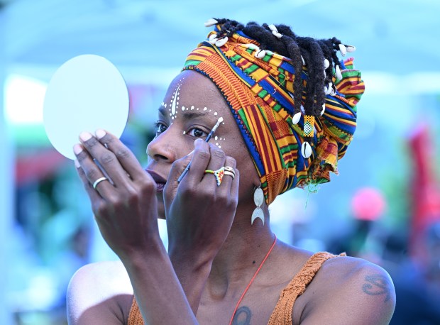 Artist Ngonda Badila of Oakland paints her face at the...