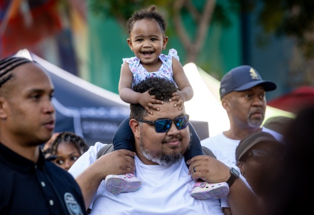 John Robertson gives his daughter Camille a vantage point to watch the battle of the bands at the Juneteenth celebration, Saturday, June 15, 2024, in the SoFa District of San Jose, Calif. (Karl Mondon/Bay Area News Group)