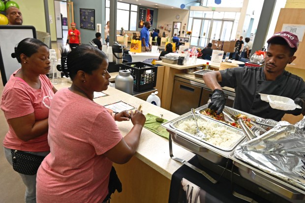 Chef Jay David serves his curry bowls to Paulette Beverly, left, and twin sister Paula, during a Juneteenth event at the Catonsville YMCA. (Kenneth K. Lam/Staff)