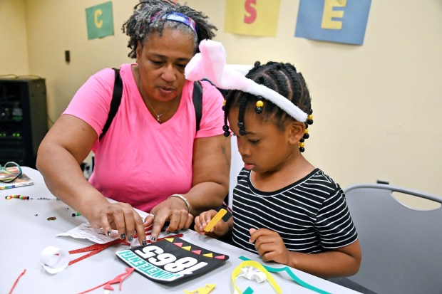 Christine Mitchell, of Washington Village, helps granddaughter Amora McGee, 6, of Essex, with a banner she is making at Juneteenth Crafts for Kids at the Cherry Hill Public Library on Tuesday. (Kim Hairston/Staff)