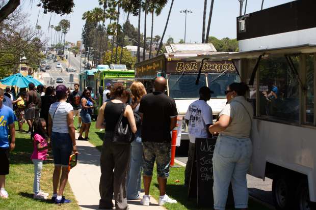 People line up to get food from a variety of...